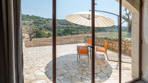 A patio with stone flooring, a table with chairs, and a large umbrella. - Villa Domus Sicilia - Charming Living (Modica)