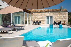 A poolside area with lounge chairs, a table, and umbrellas. - Villa Domus Sicilia - Charming Living (Modica)
