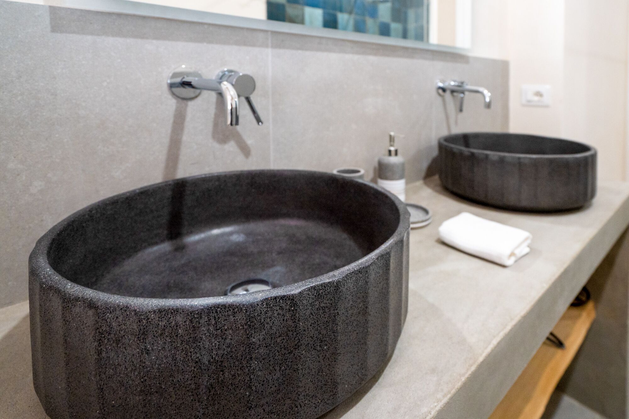 A bathroom with two black stone sinks, a mirror, and a towel on the counter.