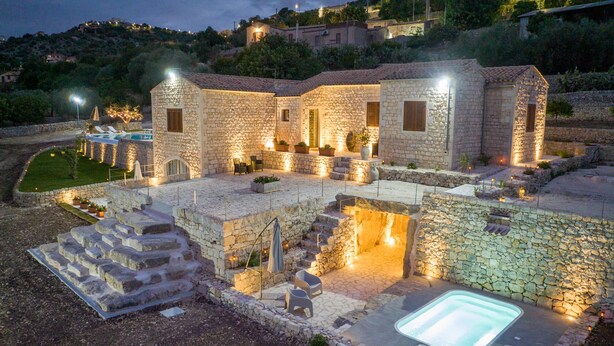 A stone villa with a swimming pool, outdoor seating, and a well-lit patio area. - Villa Domus Sicilia - Charming Living (Modica)