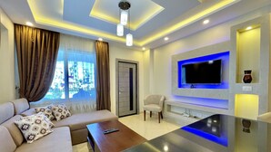 A modern living room with a sofa, a coffee table, a TV mounted on the wall, and a door. - Sharm Hills Aqua park Resort (Sharm El Sheikh)