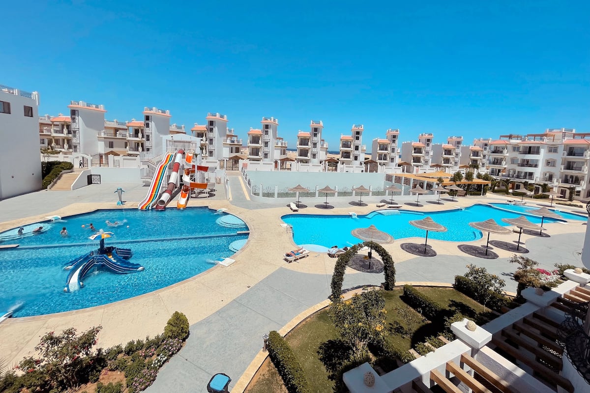 Un resort con varias piscinas, un tobogán acuático y vista al mar.