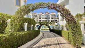 A pathway leading to a pool area, surrounded by neatly trimmed hedges and a patterned mosaic floor. - Sharm Hills Aqua park Resort (Sharm El Sheikh)