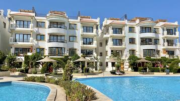 A multi-story hotel with balconies, a swimming pool, and outdoor seating areas.