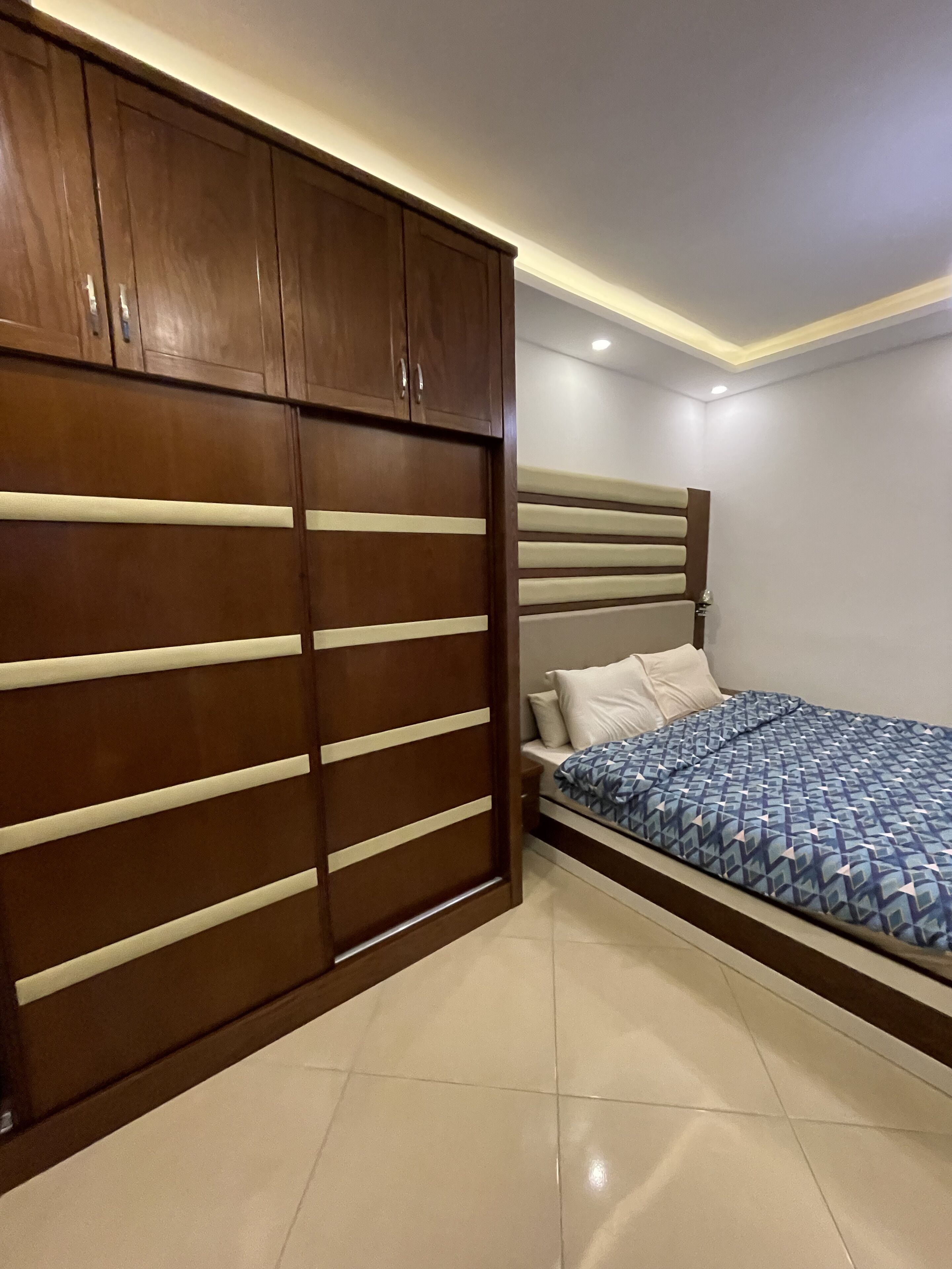 Un dormitorio con cama, armario y mesita de noche.