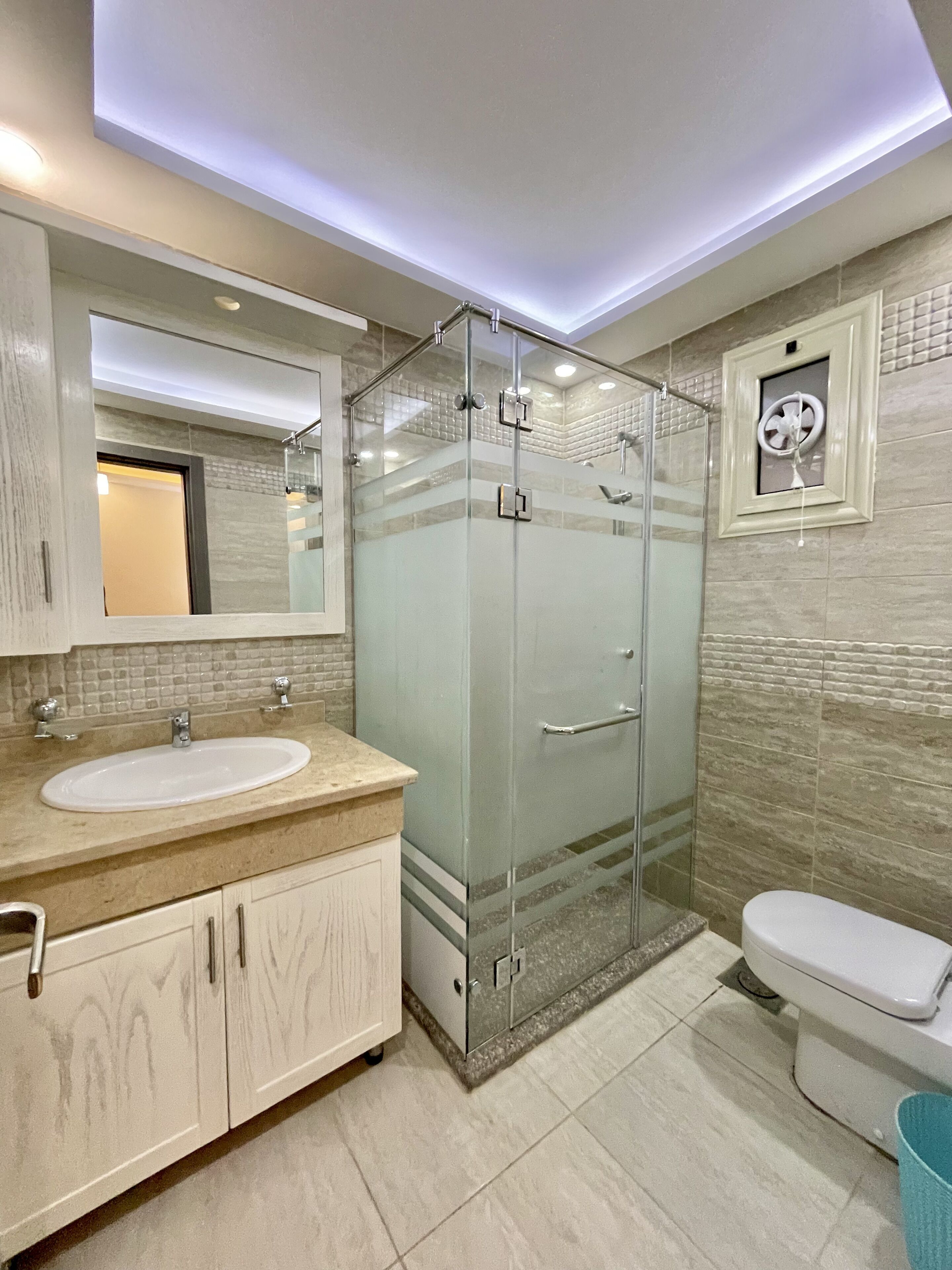 Une salle de bain moderne avec une douche à parois de verre, un lavabo avec un miroir et des toilettes.