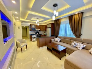 A modern living room with a sofa, coffee table, and TV. There is a kitchen area with appliances and a dining table. - Sharm Hills Aqua park Resort (Sharm El Sheikh)