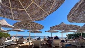 A beach with sun umbrellas and lounge chairs. - Sharm Hills Aqua park Resort (Sharm El Sheikh)