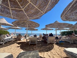 En strand med parasoller og liggestole.