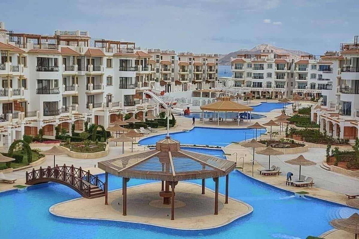 Un resort con varias piscinas, un pabellón y un puente que las conecta.