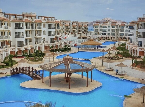 A resort with multiple swimming pools, a gazebo, and a bridge connecting the pools. - Sharm Hills Aqua park Resort (Sharm El Sheikh)