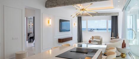 Una sala de estar moderna con una isla grande, televisión y vista al mar.