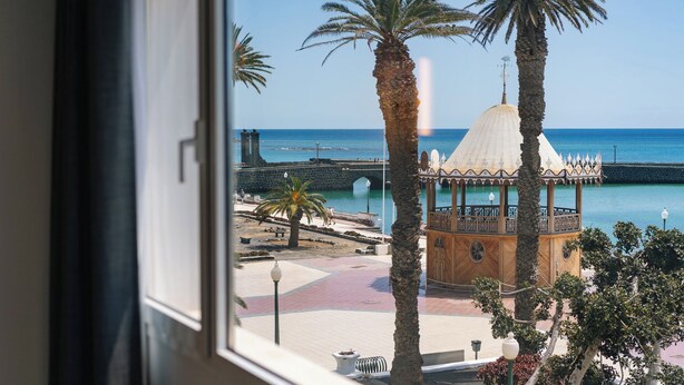 A view of a coastal promenade with a gazebo, palm trees, and a stone bridge. - Blue Marina Suites Boutique Apartments (Arrecife)
