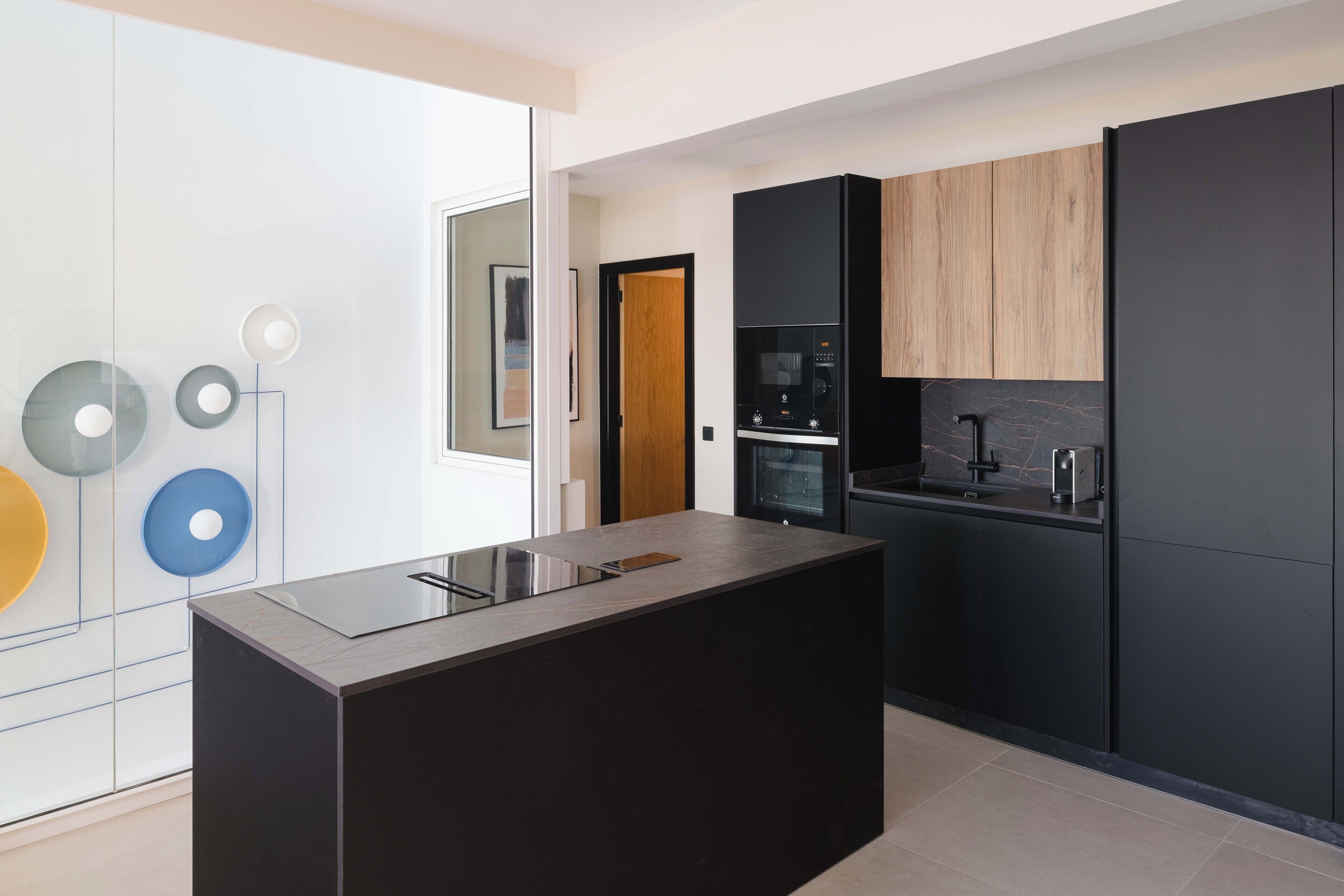 Una cocina moderna con una isla central, armarios negros y un microondas.