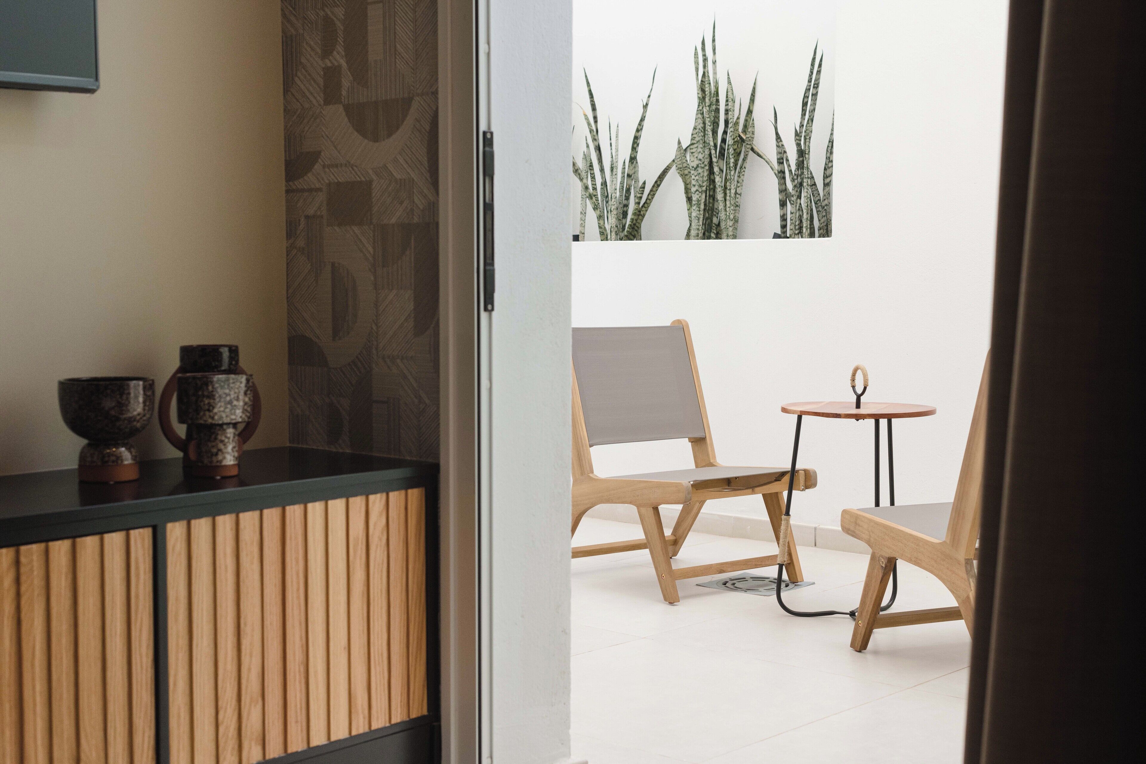 Una habitación moderna con un armario de madera, dos sillas y una mesita redonda.