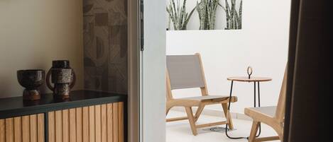 Una habitación moderna con un armario de madera, dos sillas y una mesita redonda.