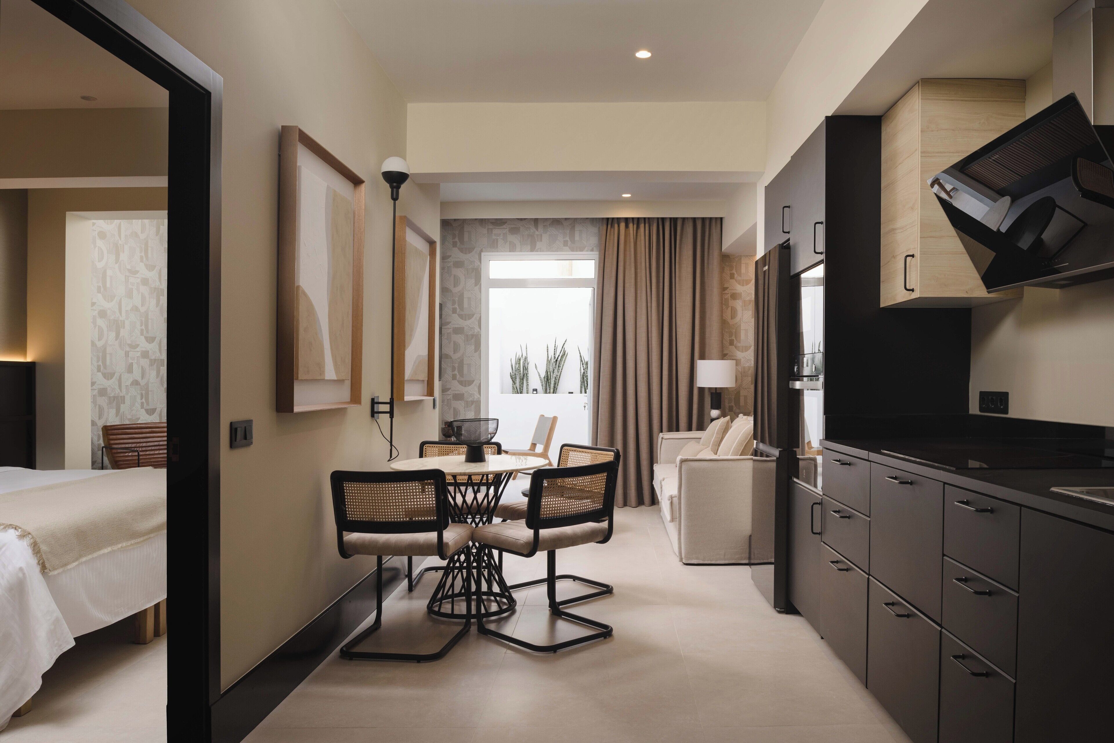 Une chambre d’hôtel comprenant un coin repas, un canapé, une télévision et un coin cuisine.