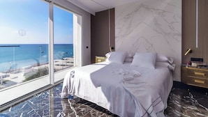 A modern bedroom with a large bed, a view of the sea, and a marble floor. - Blue Marina Suites Boutique Apartments (Arrecife)
