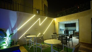 An outdoor patio area with a pool, chairs, and a kitchen visible in the background. - ABM House (Tangier)