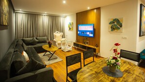 A modern living room with a sectional sofa, a wooden dining table, and a TV mounted on the wall. - ABM House (Tangier)