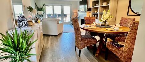 A dining area with a round table, wicker chairs, and a ceiling fan.