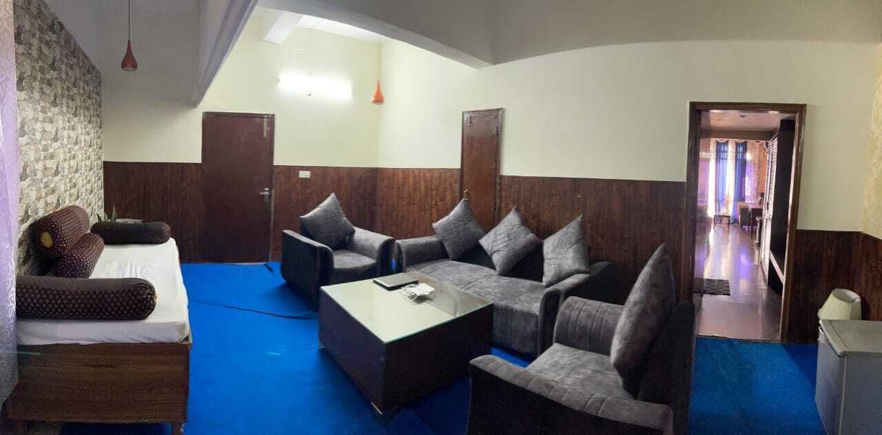 A hotel room with a blue carpet, a sofa set, a small table, and a TV.