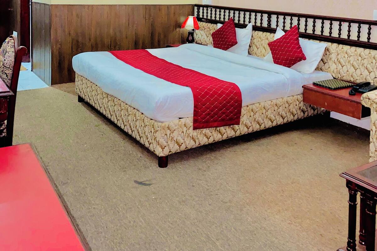A neatly arranged hotel room with a large bed, a bedside table, and a chair.