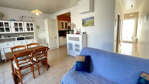 Un espace de vie compact comprenant un coin repas, une kitchenette et un canapé recouvert d’un tissu à motifs.