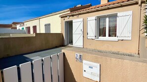 Un immeuble résidentiel à la façade beige, doté de volets blancs et d’une boîte aux lettres bien visible.
