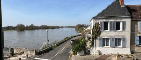 A riverside building with a paved area, a stone wall, and a clear view of the river.