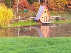 Situated by the water, this charming home offers a serene natural setting surrounded by trees with autumnal foliage.