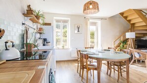 A modern kitchen with wooden cabinets, a dining area with a round table, and a staircase leading to an upper level.