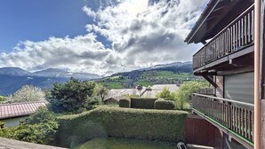 Un balcon donnant sur un paysage montagneux, une clôture en bois et un bâtiment doté d’un balcon.