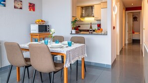 Zona de dinar amb una taula preparada per a quatre persones, microones i cuina al fons.