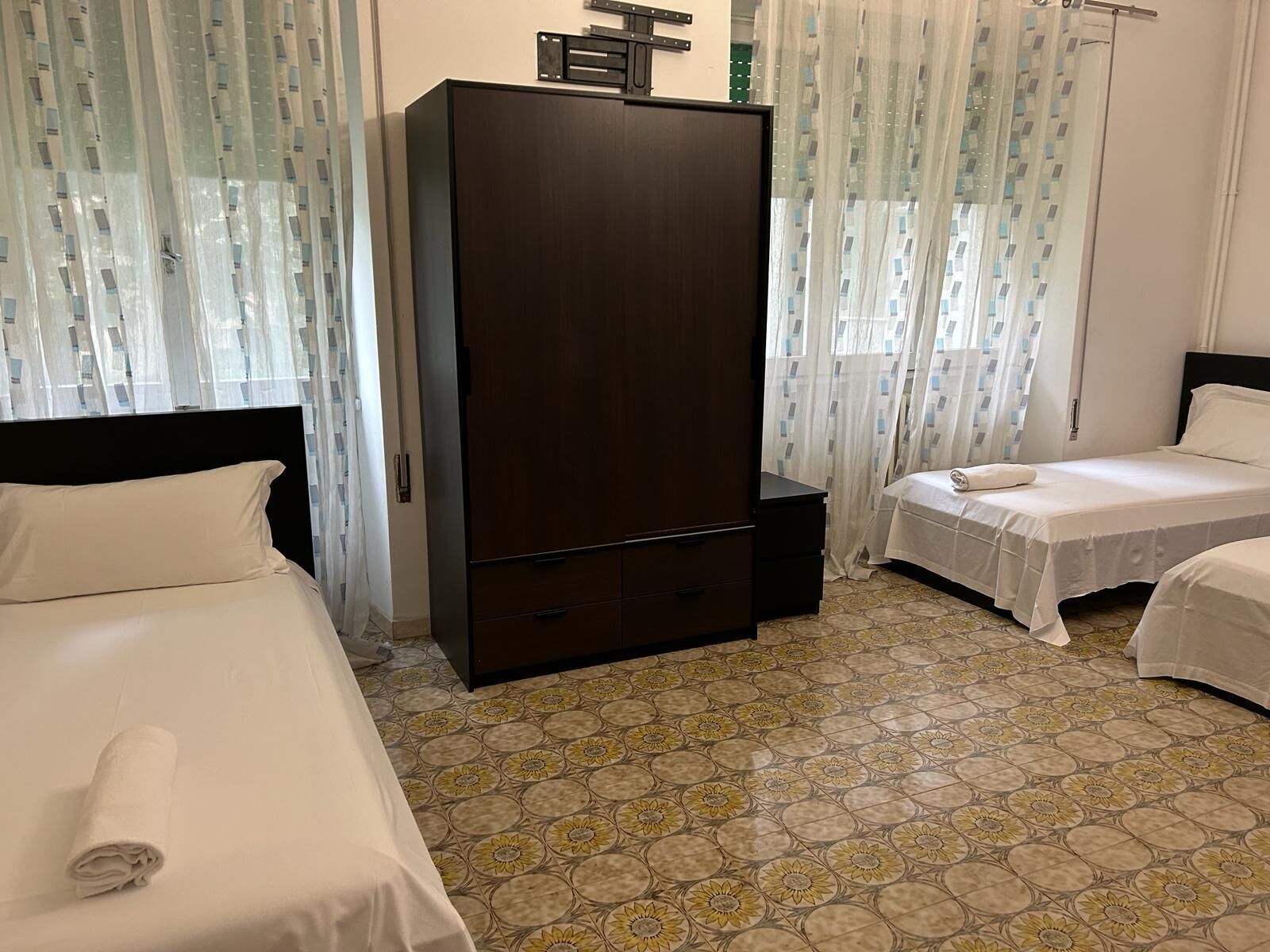 A hotel room with two beds, a wardrobe, and a patterned floor.