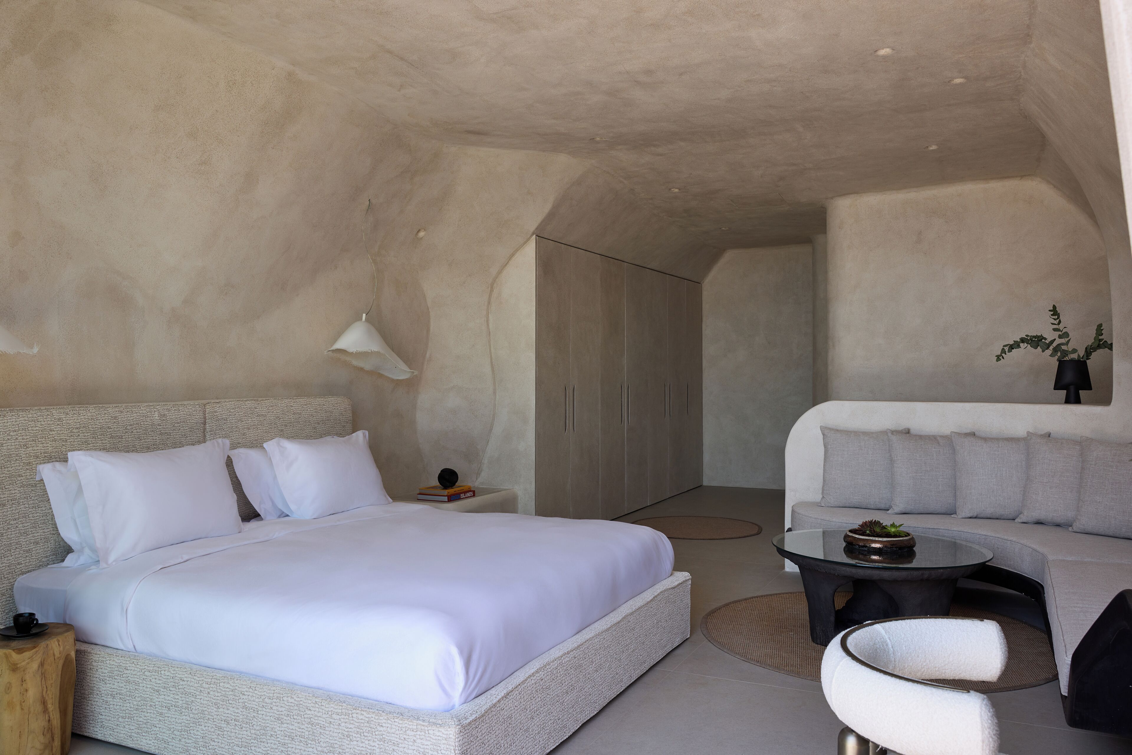 Een moderne slaapkamer met een groot bed, een bank, een bijzettafeltje en een kledingkast.