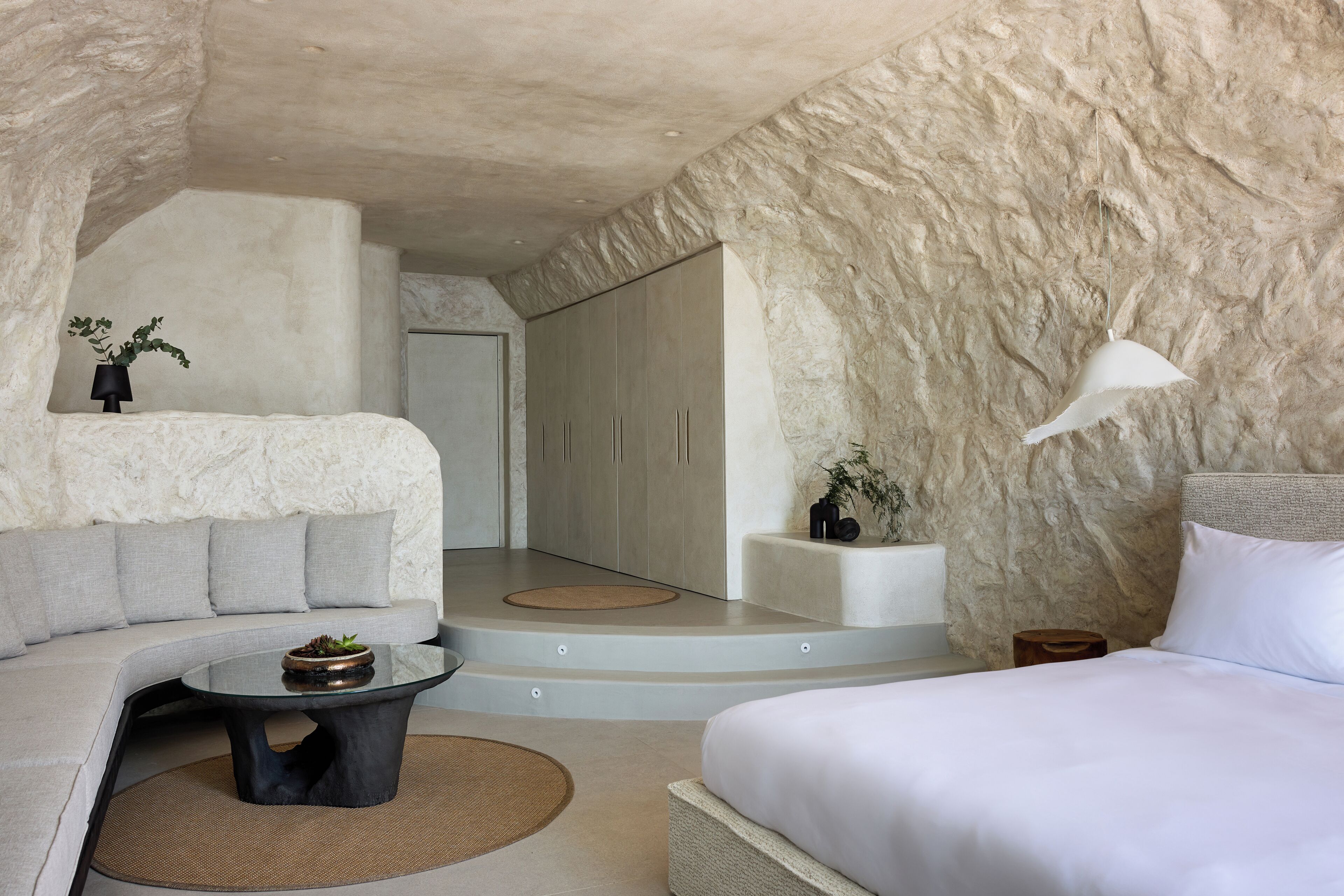 Une chambre moderne avec un mur en pierre, un canapé, un lit et une petite table.