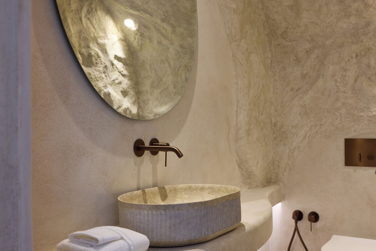 A bathroom with a marble sink, a large mirror, a toilet, and a towel on the counter.