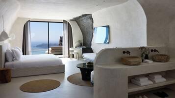 Un dormitorio moderno y minimalista con una cama grande, una zona de estar y vistas al mar.