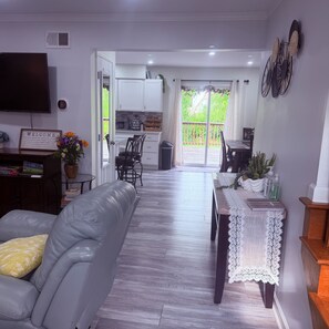 A modern living room with a grey sofa, a dining table with a lace table runner, and a kitchen in the background. - Sweet Retreat (Elizabethtown)