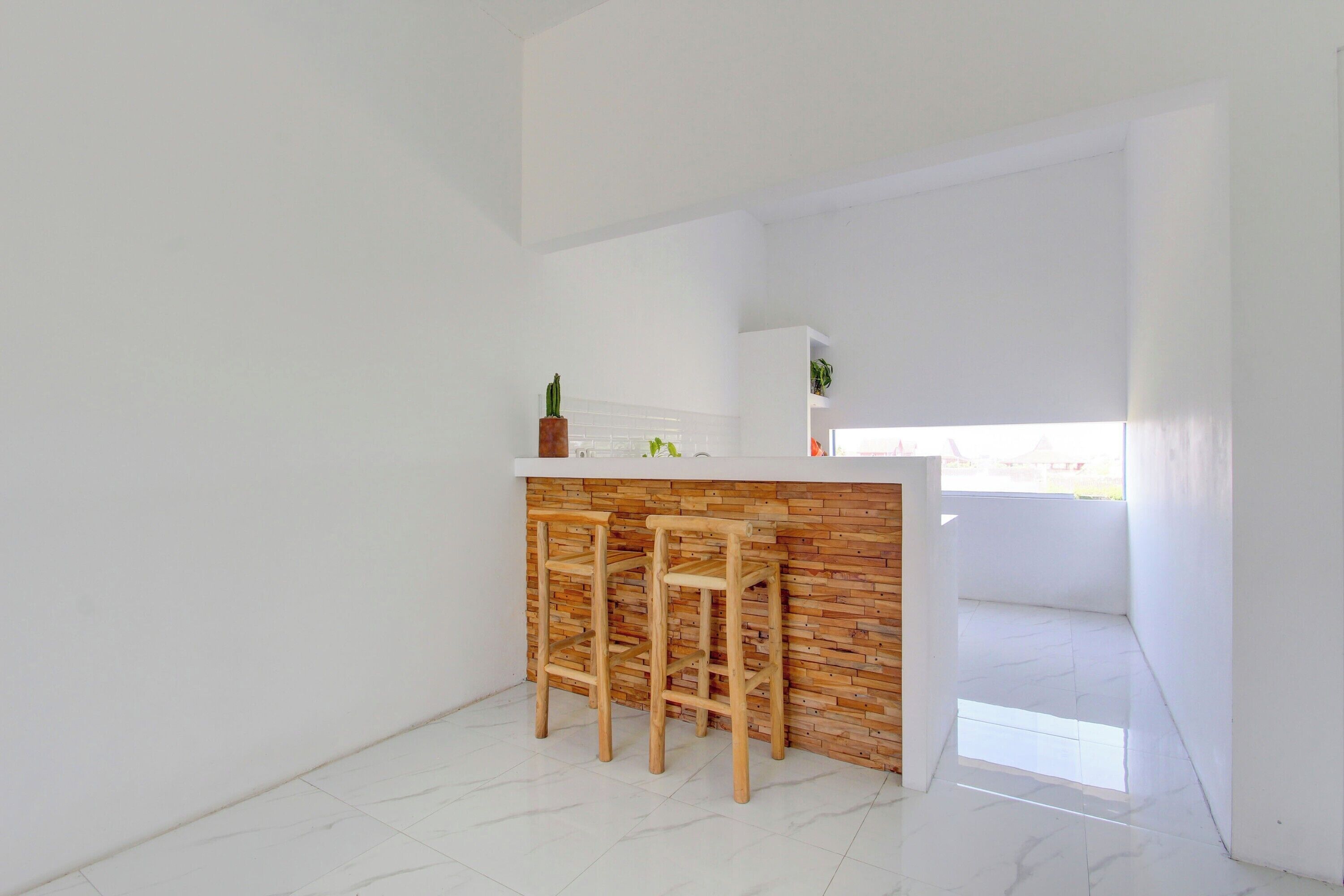 Una cocina con encimera blanca, taburetes de madera y una pared de ladrillo decorativa.