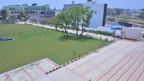 Un patio con zona pavimentada, árboles y un edificio al fondo.