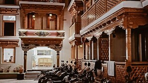 En innergård med en rad uppställda motorcyklar, en byggnad med traditionell arkitektur och utsikt över en hotellentrén.