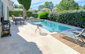 A swimming pool with a wooden deck, a table, and chairs. - Awesome home in Saint-Rémy-de-Provence (Saint-Rémy-de-Provence)