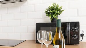 A kitchen counter with a plate of macarons, a bottle of wine, two glasses, and a bouquet of tulips. - Hideaway Apartment - Terrace with Garden & Parking by Rentujemy (Lódz)