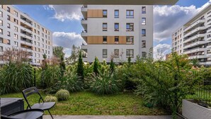 A modern apartment building with a rooftop garden, outdoor seating area, and a view of neighboring buildings. - Warsaw Airport Studio with Private Terrace by Rentujemy (Warszawa)