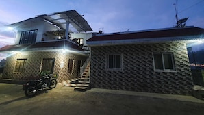 Una casa de dos pisos con un balcón y una motocicleta estacionada frente a ella.
