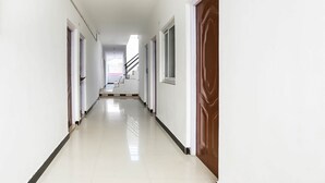 Un pasillo largo y estrecho con paredes blancas y un piso brillante, que conduce a una escalera.