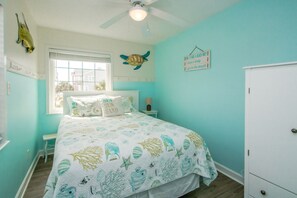 A bedroom with a bed, a window, a ceiling fan, a wall decoration, and a cabinet. - Followin' The Son Too - 3 BR in Calinda Cay; Comm. Pool & Ocean Views (North Topsail Beach)
