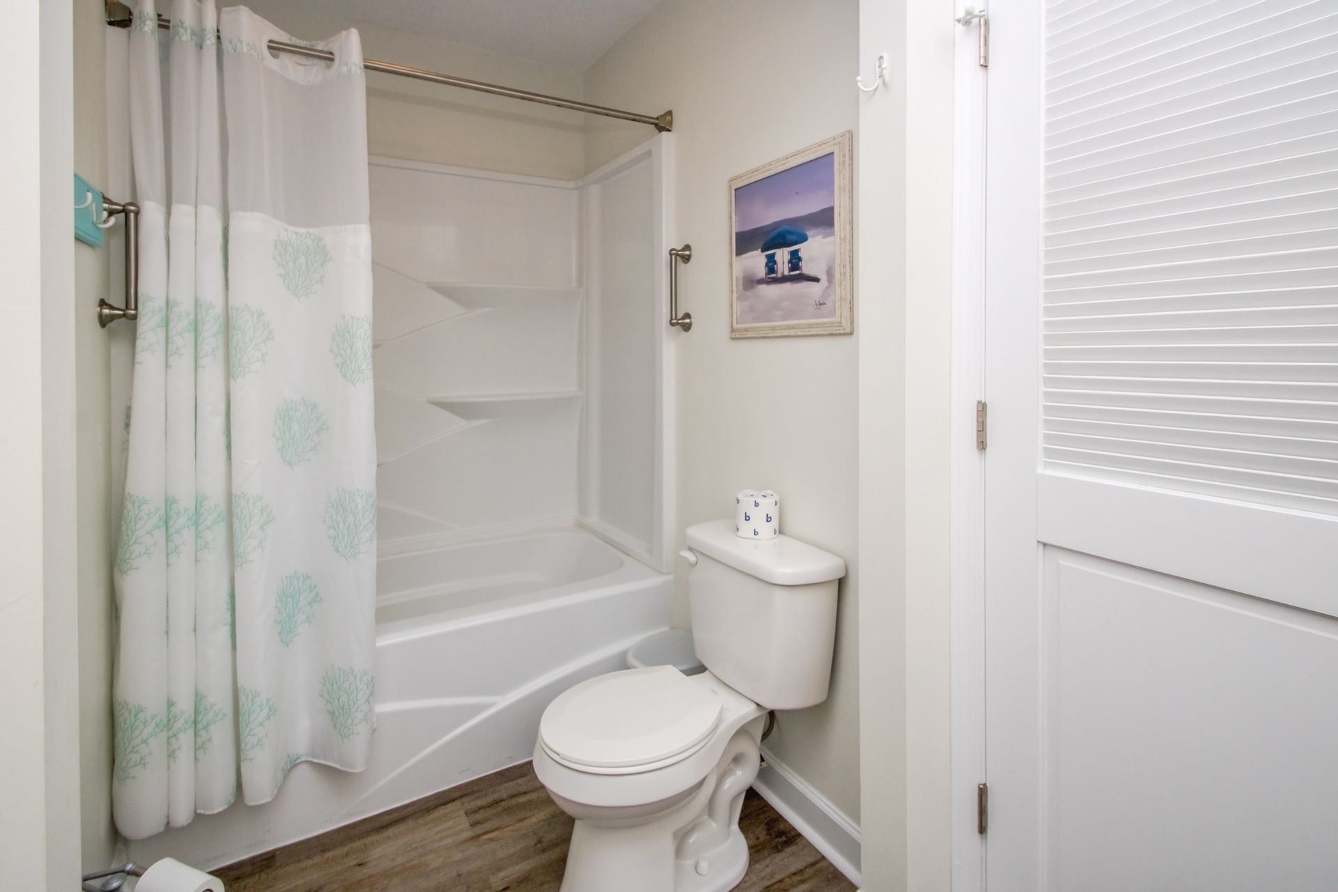 A bathroom with a shower, toilet, and a framed picture on the wall.